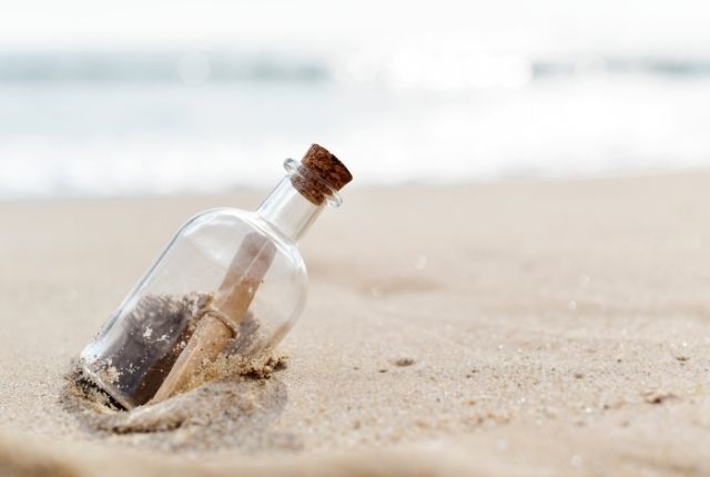 eine Flaschenpost im Sand am Strand