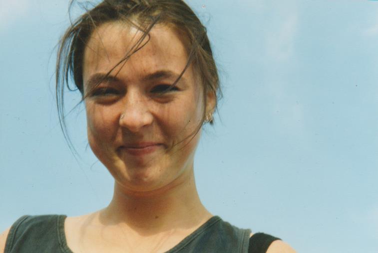 eine junge Frau lächelt in die Kamera, im Hintergrund blauer Himmel