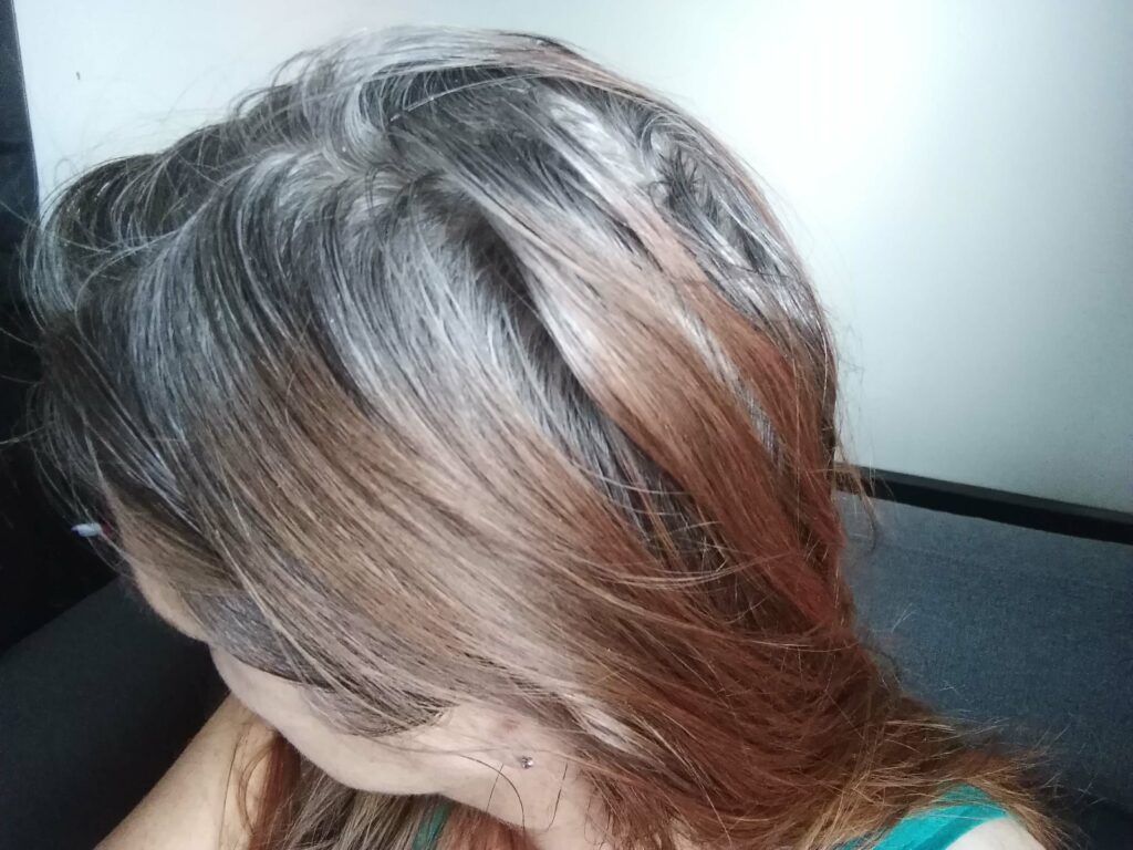 Frauenkopf von oben, rote lange Haare mit grauem Ansatz