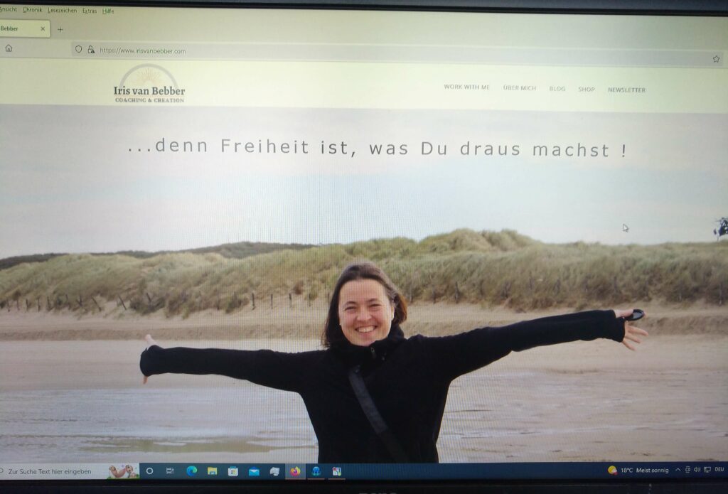 Startseite einer Homepage. eine Frau steht mit ausgebreiteten Armen und lachend am Strand, im Hintergrund sind Dünen zu sehen