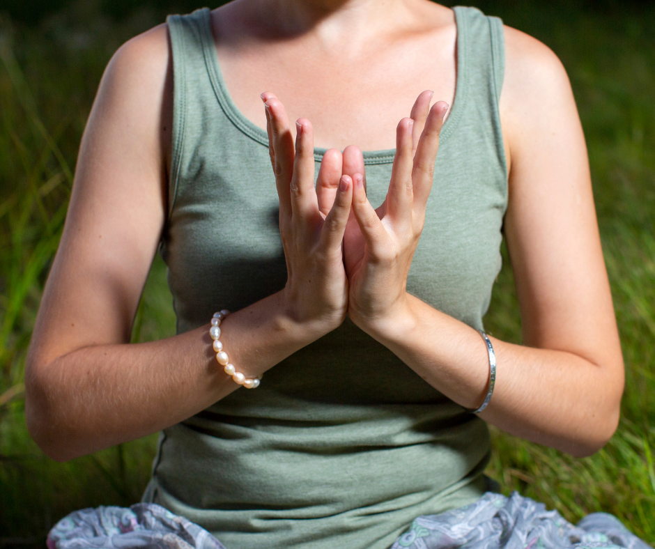 eine Frau hät ihre Hände vor den Körper im Padma-Mudra um das Herz Chakra zu aktivieren