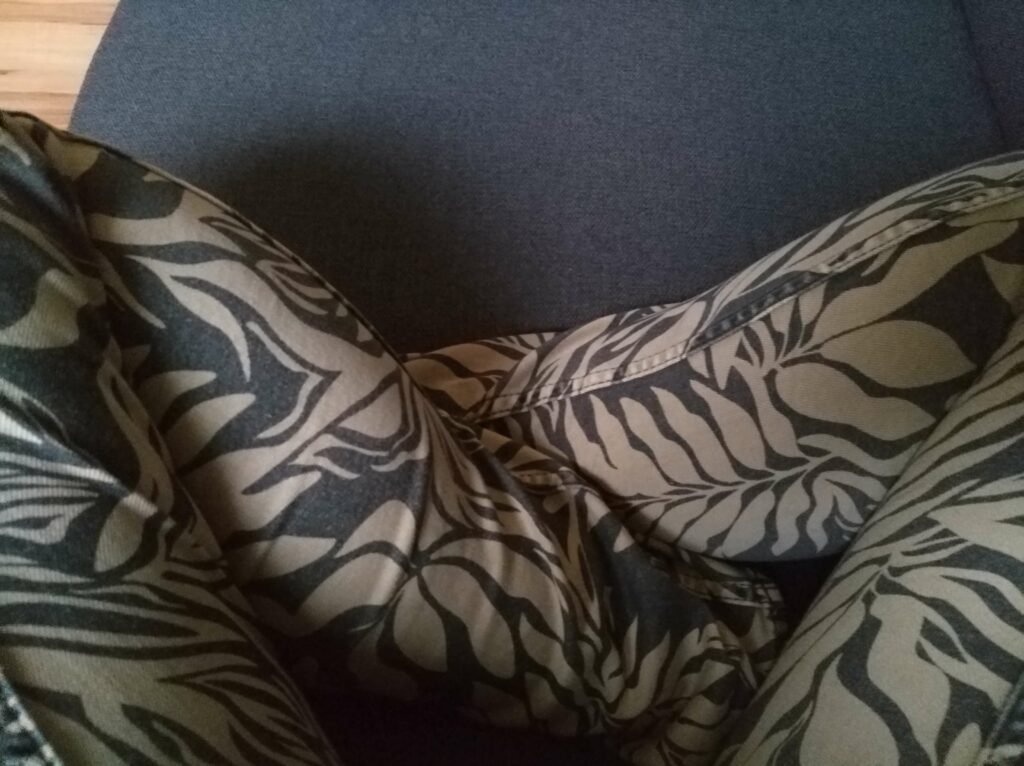 jemand mit einer gemusterten Hose sitzt im Schneidersitz im Sessel