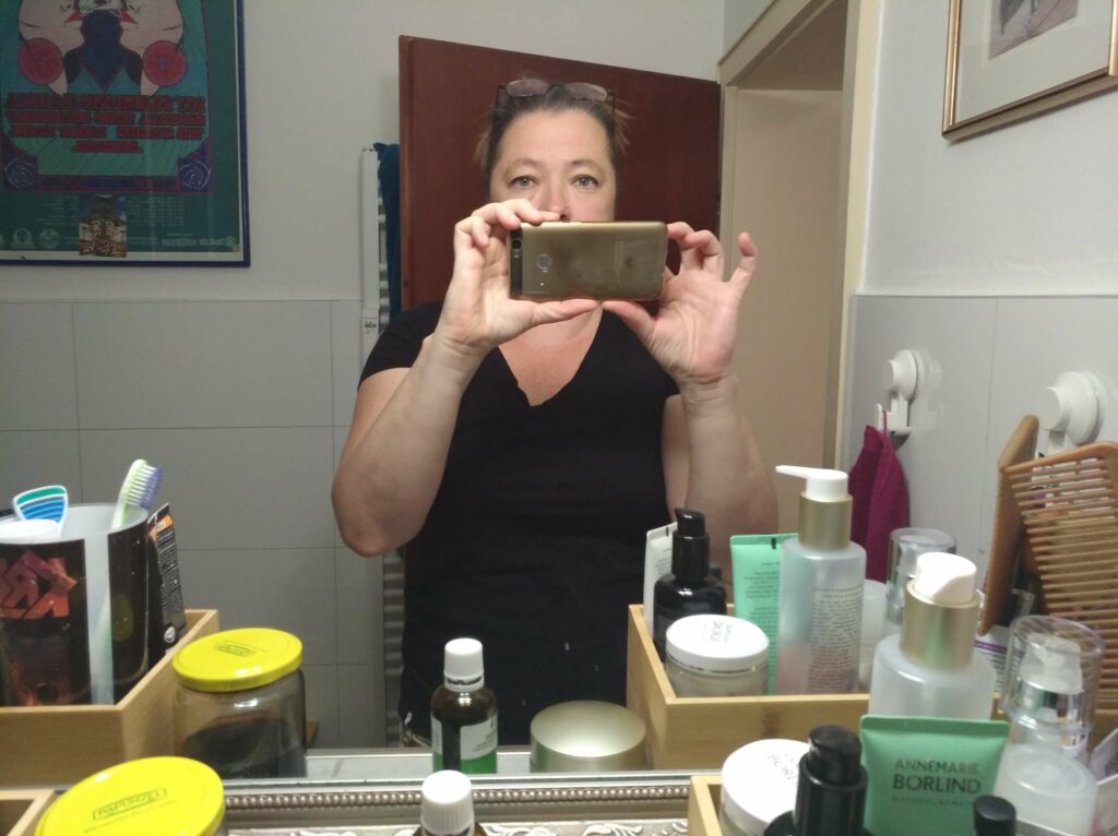 eine Frau macht ein Handy Selfie im Badezimmerspiegel