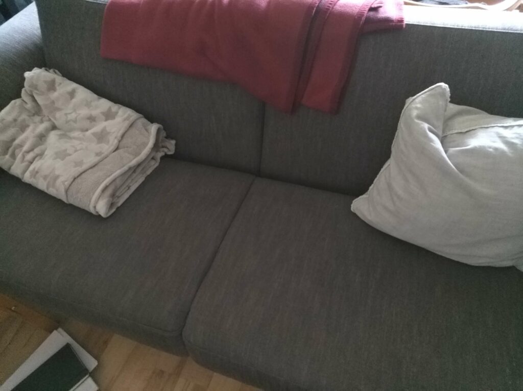 graue Couch mit Decke und Kissen